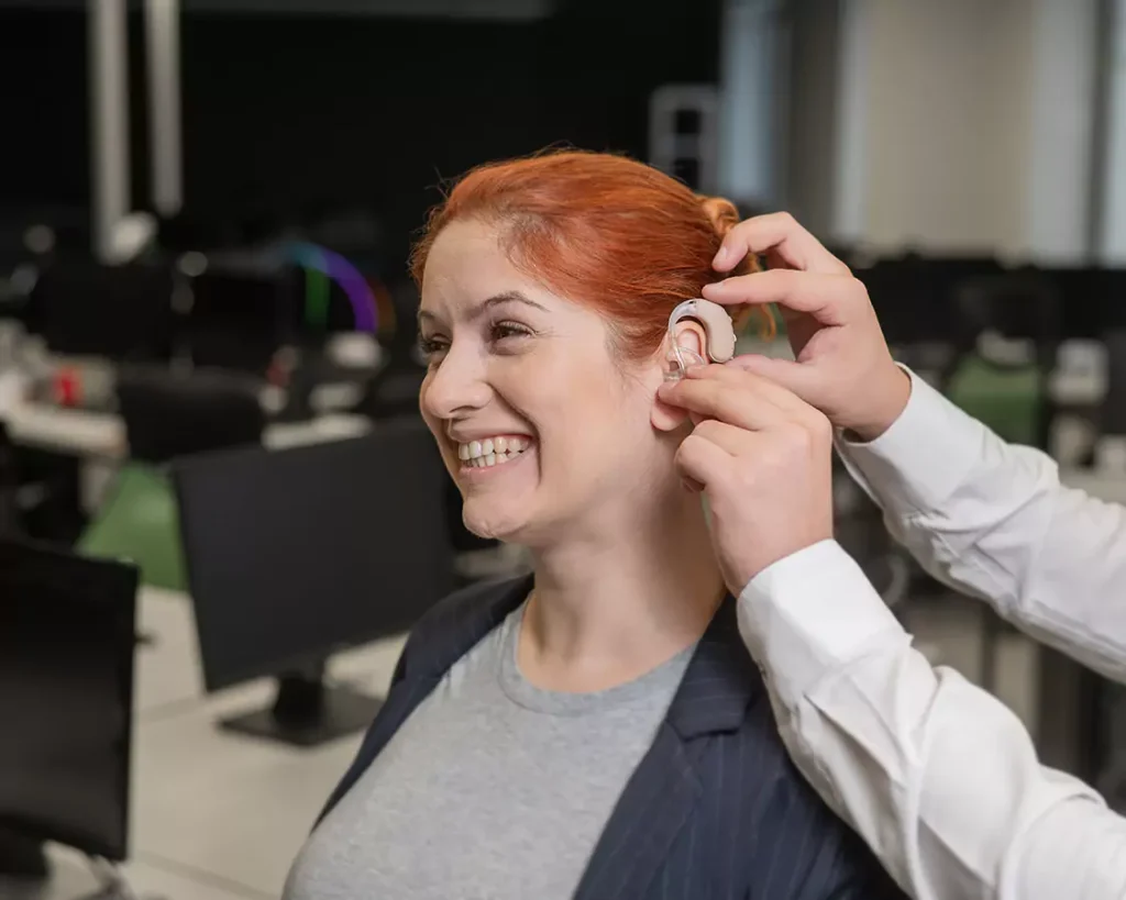 A disabled woman smiling while having someone put her ear support
