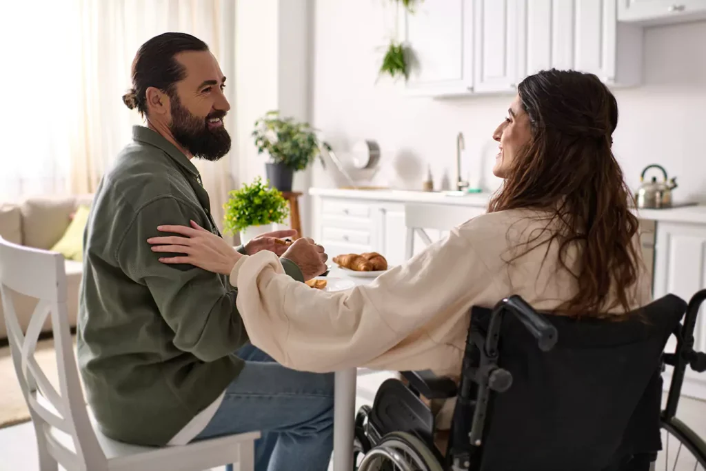 A disabled woman sitting in her wheelchair and her support worker in the dining table